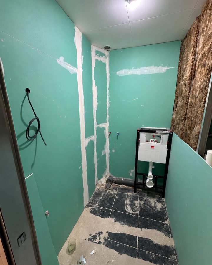 Baño en obra, con las paredes de placa de yeso y la cisterna empotrada aun vista.