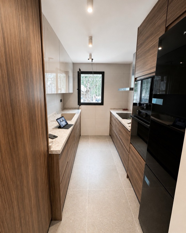 Cocina terminada con muebles de madera, encimera clara y electrodomésticos integrados.