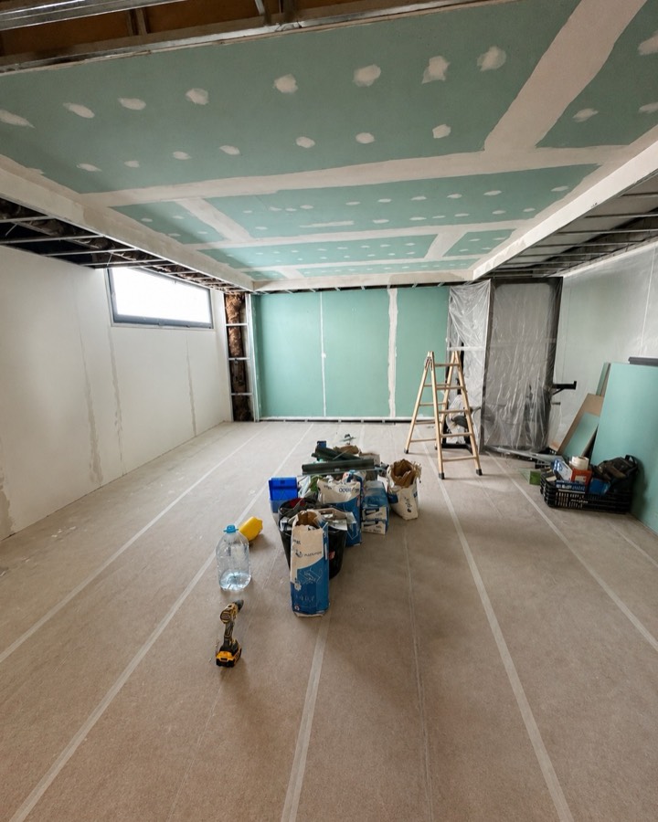 Sala en obra con el falso techo de placa de yeso montado y el suelo protegido.