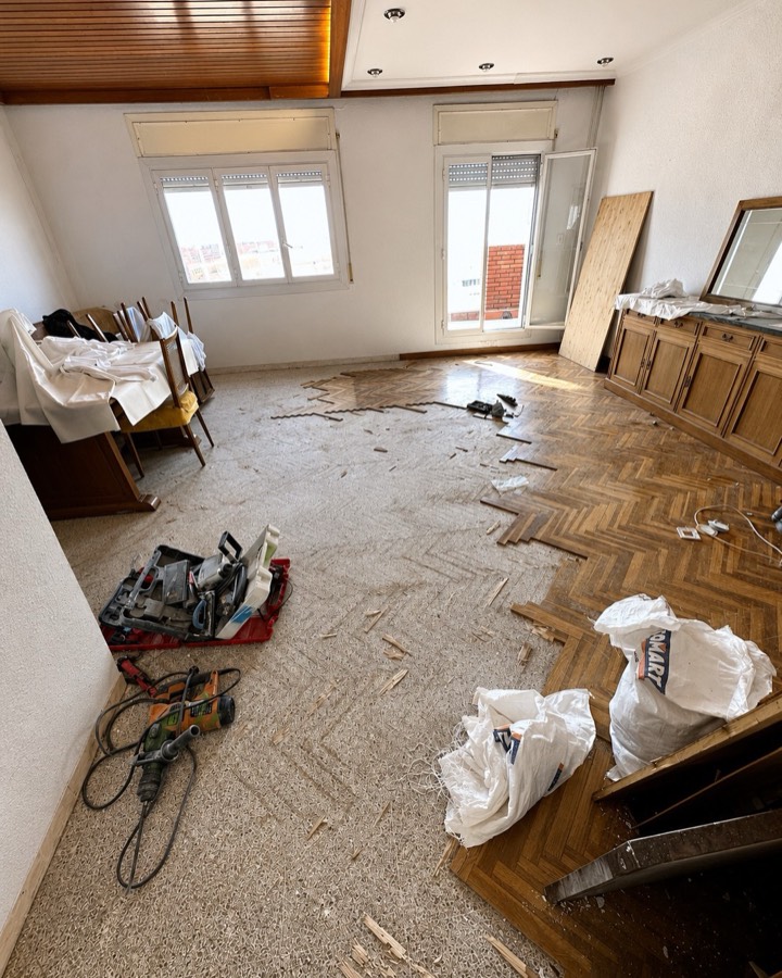 Salón durante la obra, con el parqué antiguo levantado y material de trabajo en el suelo.
